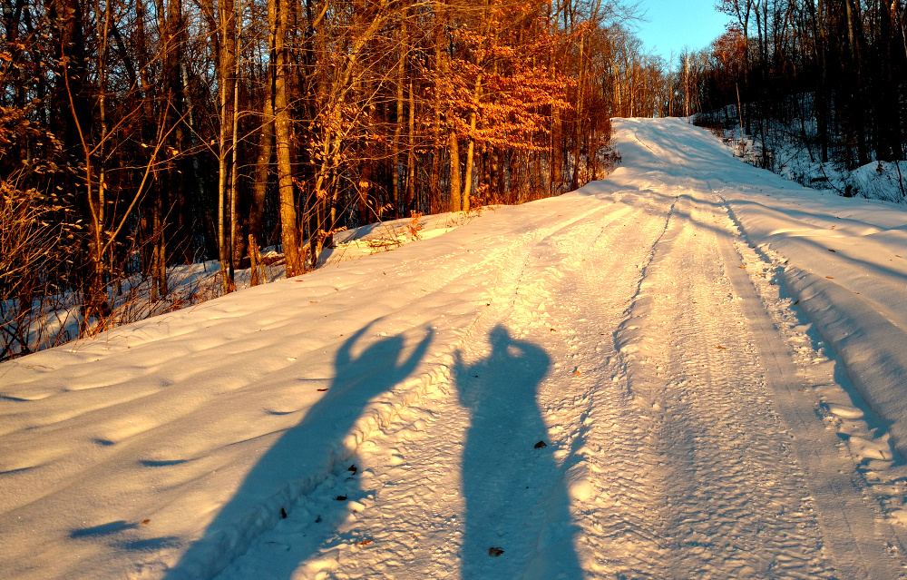 Photo of Mama and Papa in silhouette on the snow-covered road leading down from the look-out tower at Parc Mont-Morisette