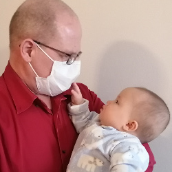 Baby touches her masked father