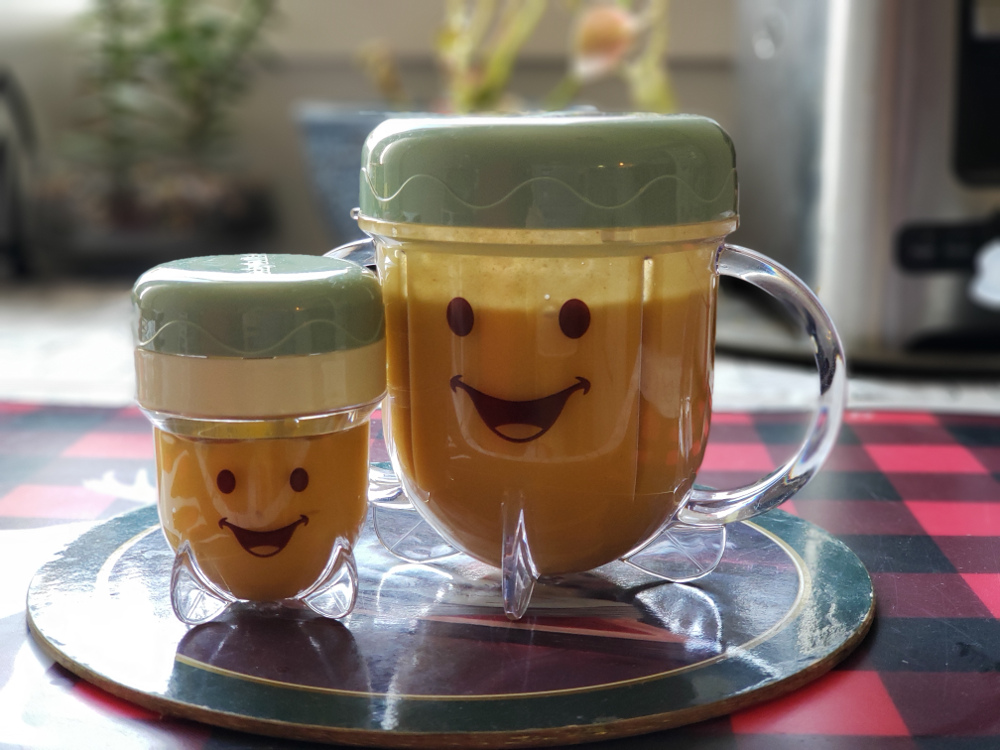 Photo of small and large plastic jars with smiley faces of home-made baby-food.