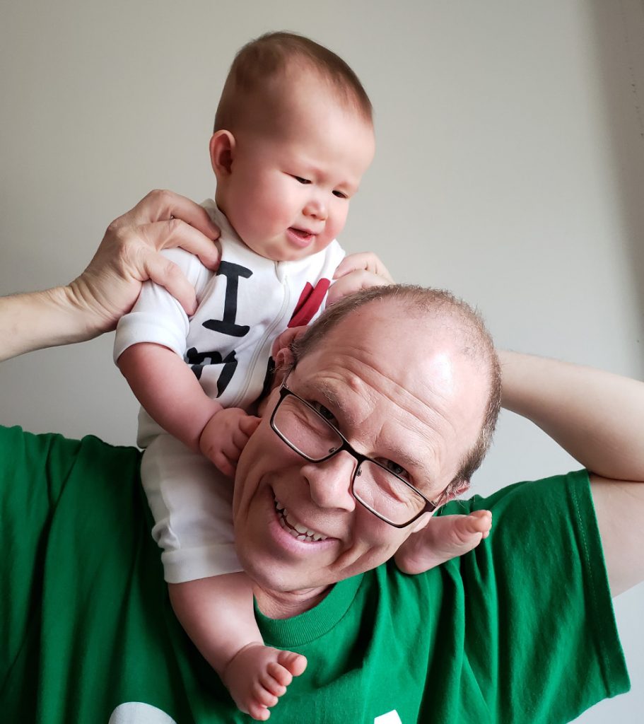 Photo of baby Baobao wearing I heart Mom onesie while riding Papa Zesser's shoulders.