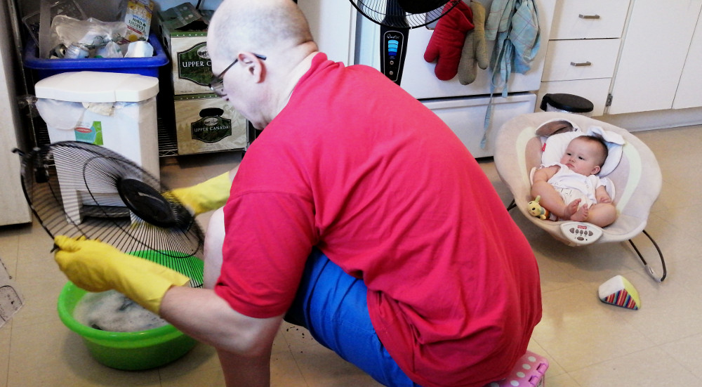 Photo of Papa Zesser cleaning a fan as baby Baobao oversees.