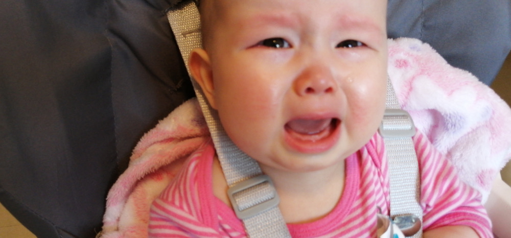 Photo of Baby Baobao crying while strapped in a chair.