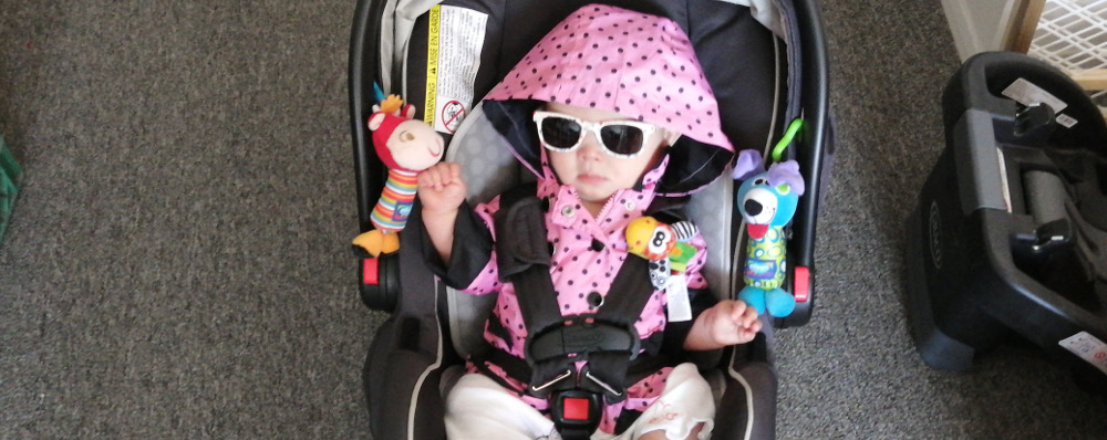 Photo of Baby Baobao, strapped in child-seat with fist raised in protest.