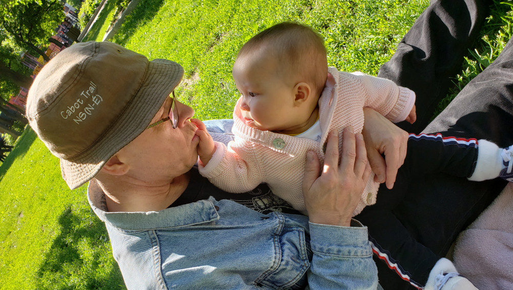 Photo of baby Baobao in Papa Zesser's arms, touching his face while in a park.