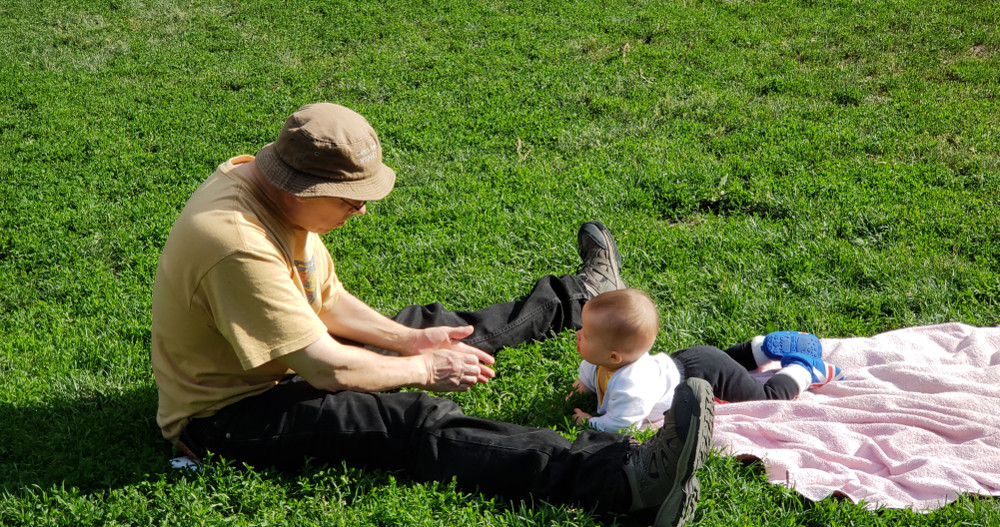 Photo of baby Baobao with Papa Zesser on the grass in a park.