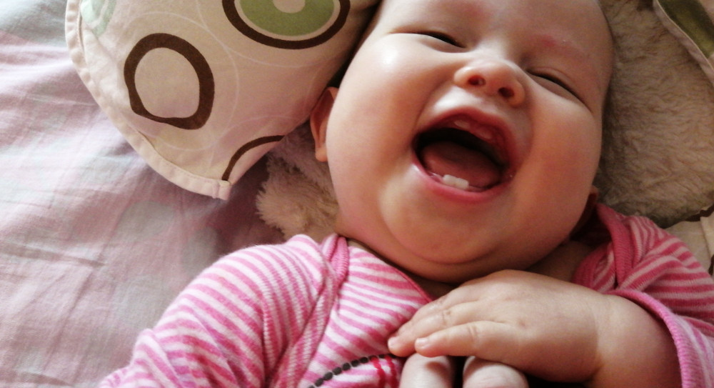 Photo of laughing baby Baobao showing two teeth each on top and bottom.