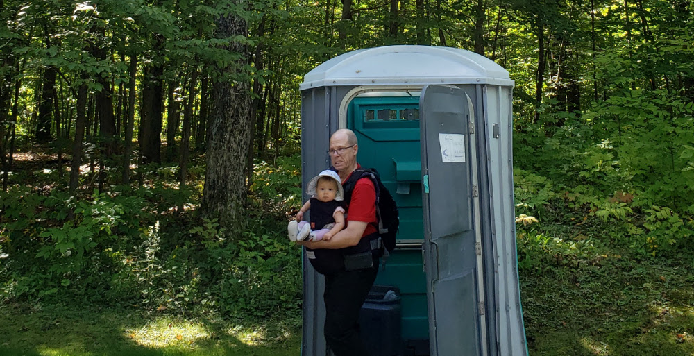 Photo of Papa Zesser holding baby Baobao as they exit a port-o-potty in Gatineau Park.