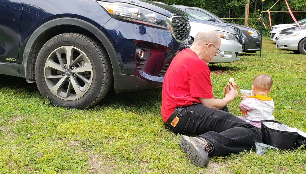 Detail of photo of Papa Zesser helping Baobao eat in front of their rental car.