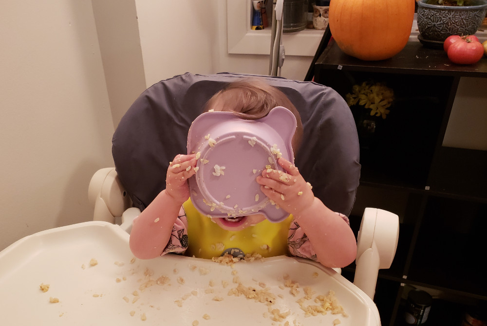 Photo of Toddler Baobao making a very messy stab at self-feeding, November 18, 2020.